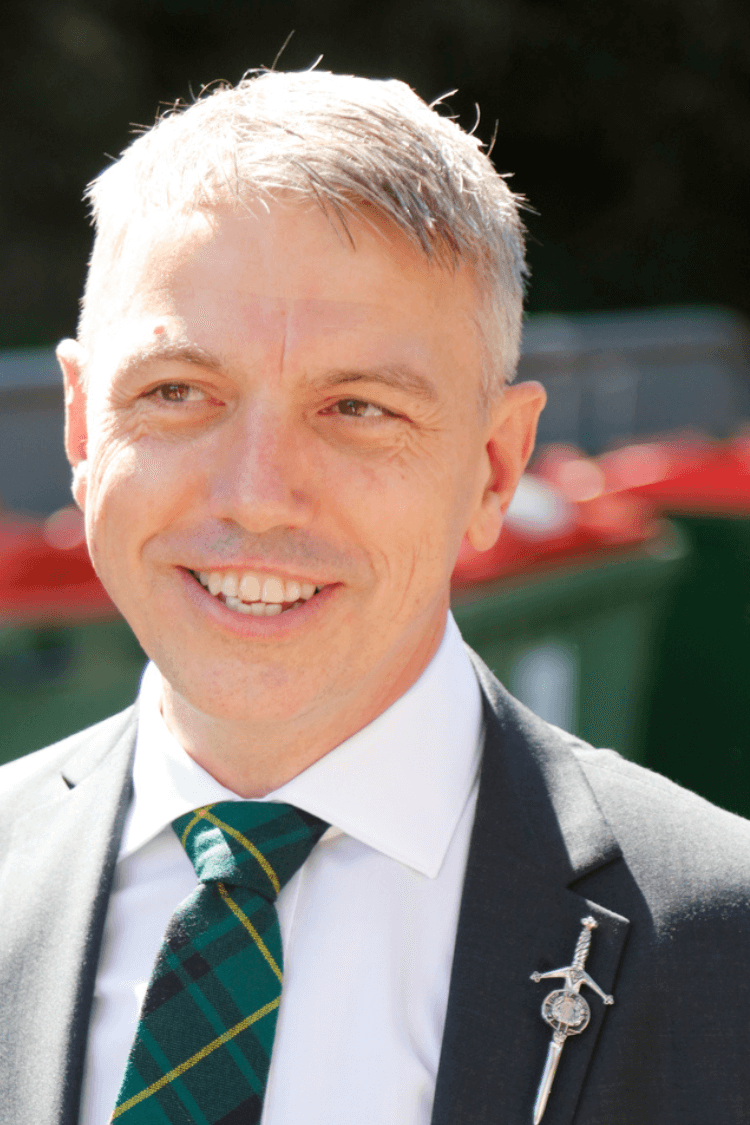 A man in a white short, black jacket and green tie. 