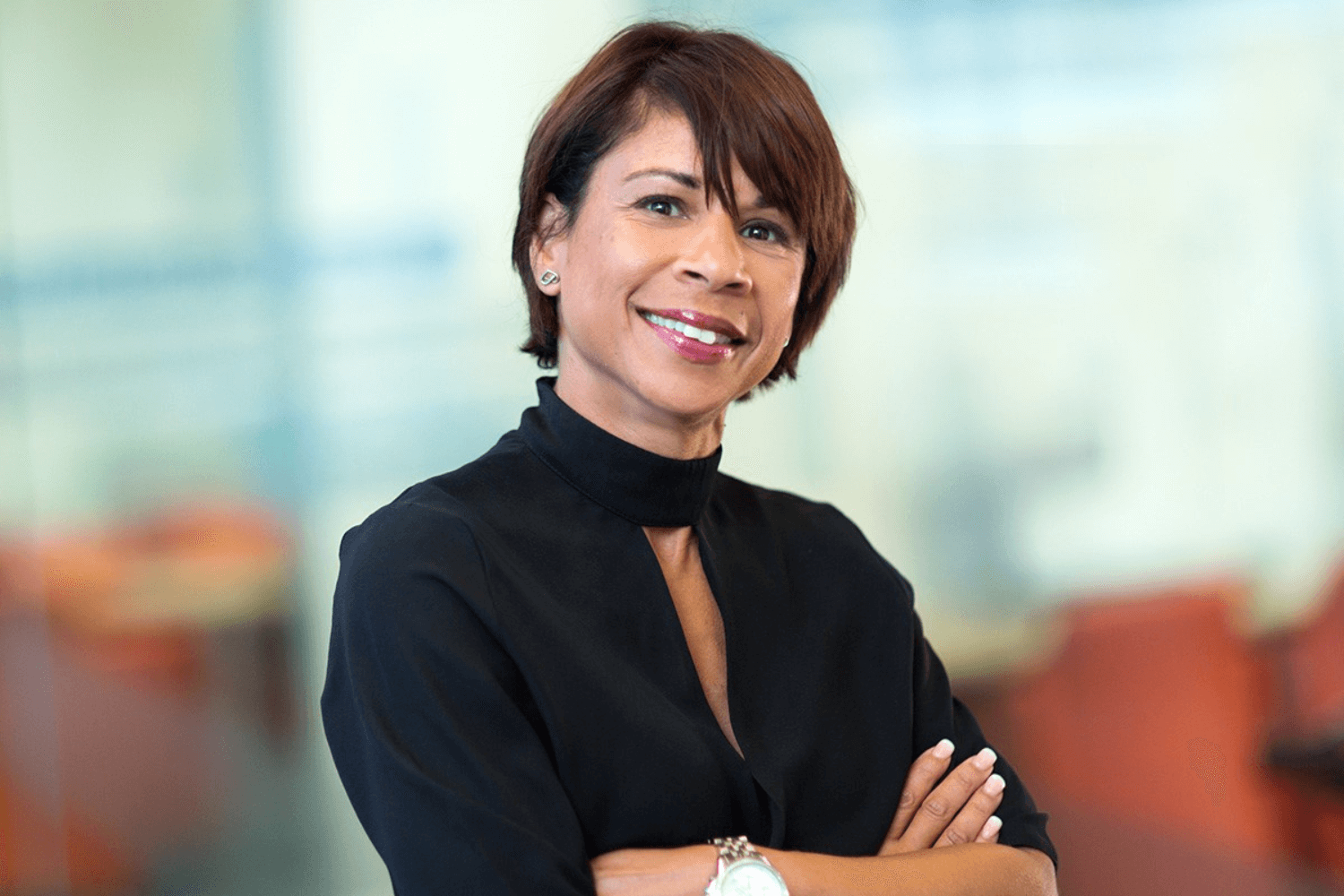 A woman with short brown hair and her arms folded, looking at the camera. 
