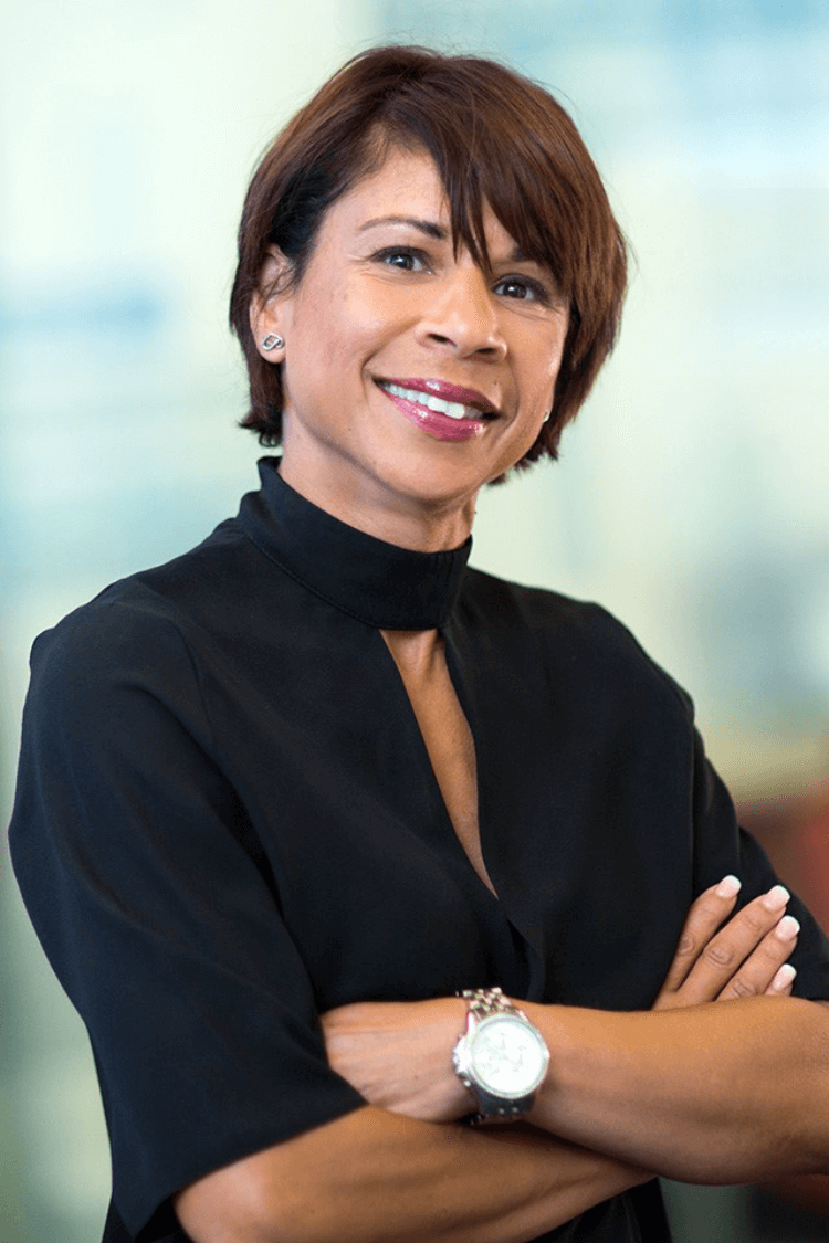 A woman with short brown hair and her arms folded, looking at the camera. 