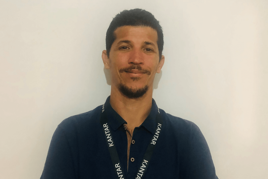 Um homem de cabelo escuro e barba castanha escura. Veste uma camisa azul-marinho e vê-se também o seu cordão de segurança Kantar.