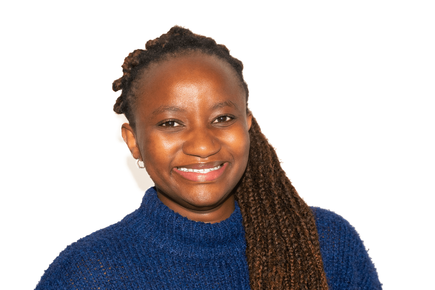 Carol hat langes dunkles Haar, das zu Zöpfen geflochten ist. Sie trägt einen marineblauen Rollkragenpullover. 