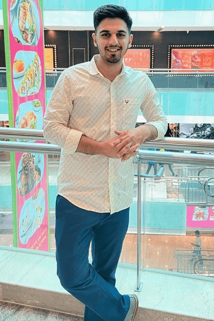 Ein Mann mit weißem Hemd und Jeans steht an einem Balkongeländer in einem Einkaufszentrum.